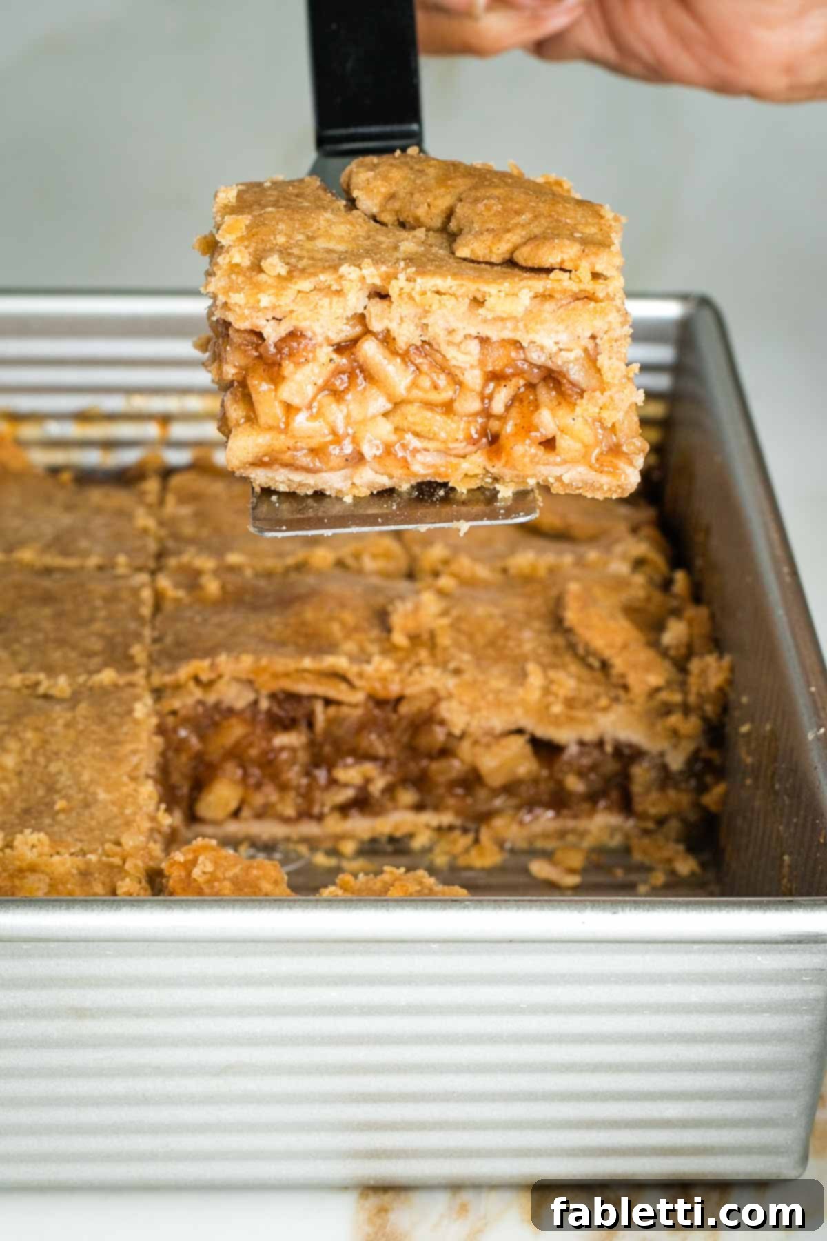 Baked apple pie bars stored neatly in an airtight container in the refrigerator.