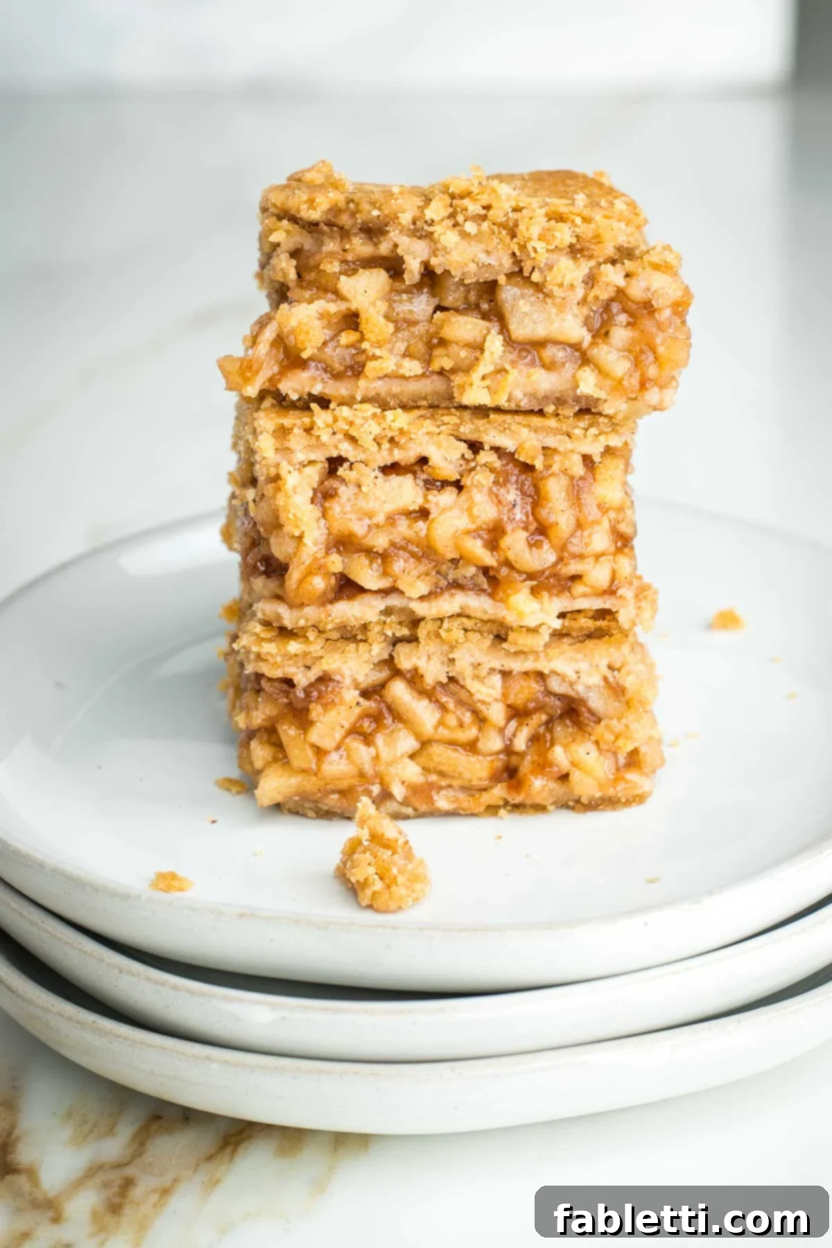 Three individual apple pie bars stacked, clearly showing the jammy apple filling and flaky crust layers.