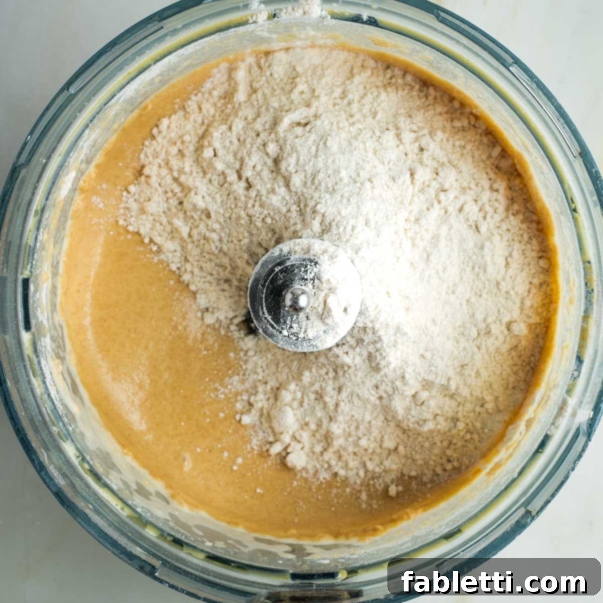 Pillowy Sweet Challah Crown 13 The remaining flour, precisely measured, is sprinkled over the partially mixed dough in the food processor bowl, ready for the final knead.