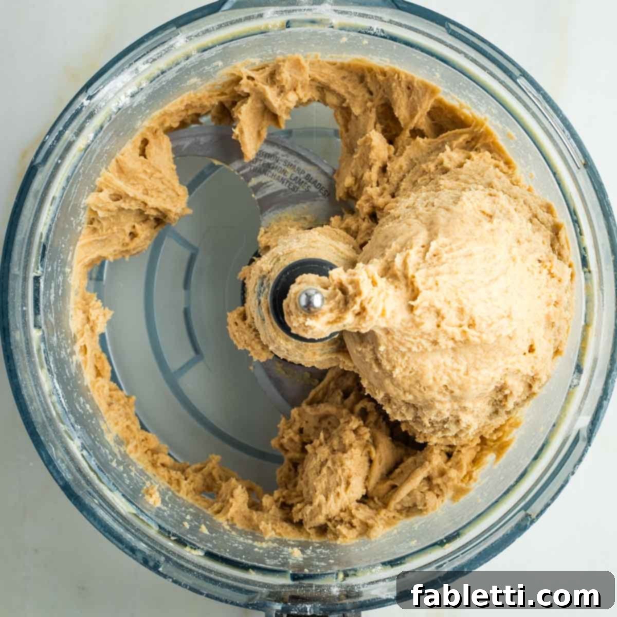 Pillowy Sweet Challah Crown 14 Bread dough clinging to the sides of a food processor bowl, indicating it might need a little more flour for optimal kneading.