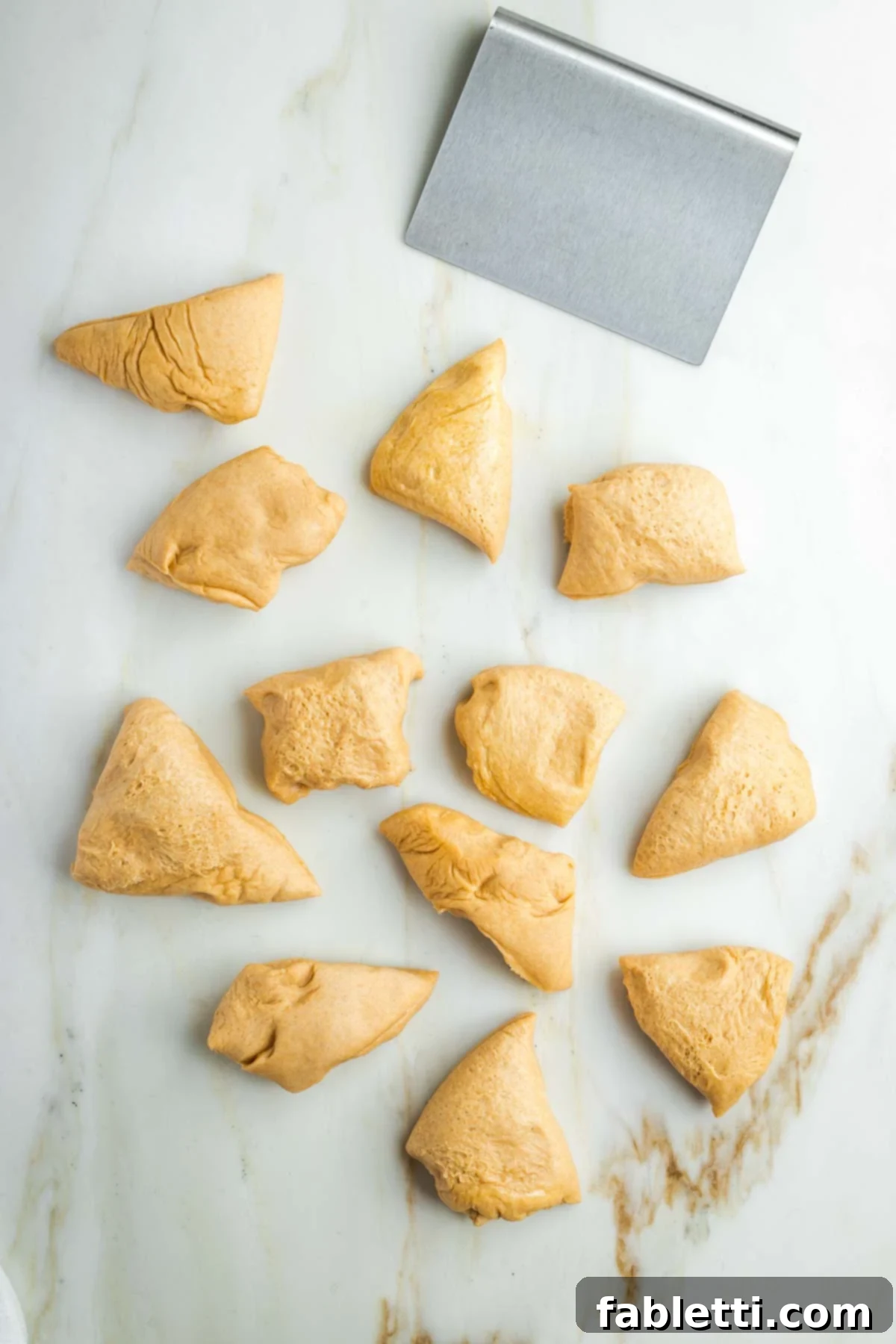 Pillowy Sweet Challah Crown 21 A dough scraper divides the risen challah dough into 12 small, equal pieces, ready for shaping and braiding.