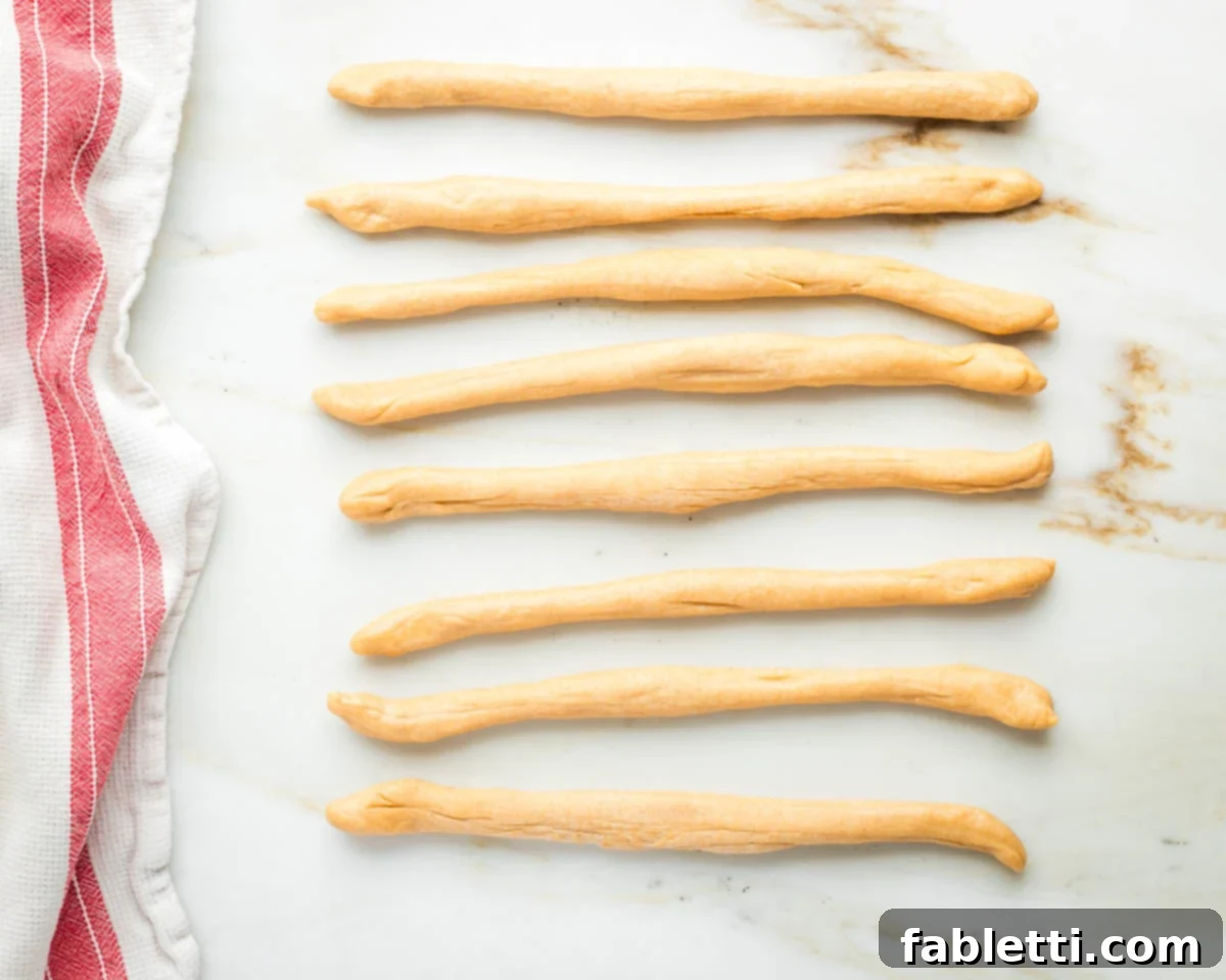 Pillowy Sweet Challah Crown 24 Eight challah dough ropes, meticulously rolled to be of equal length and consistent thickness, laid out side by side.