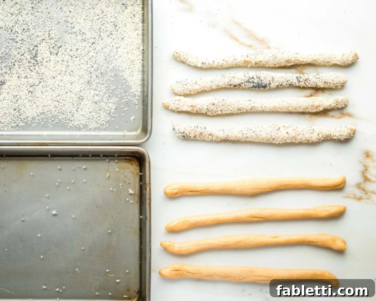 Pillowy Sweet Challah Crown 25 A shallow pan of water and a separate pan of sesame and poppy seeds are prepared, with several dough strands already half-covered in the seed mixture, ready for the next step.