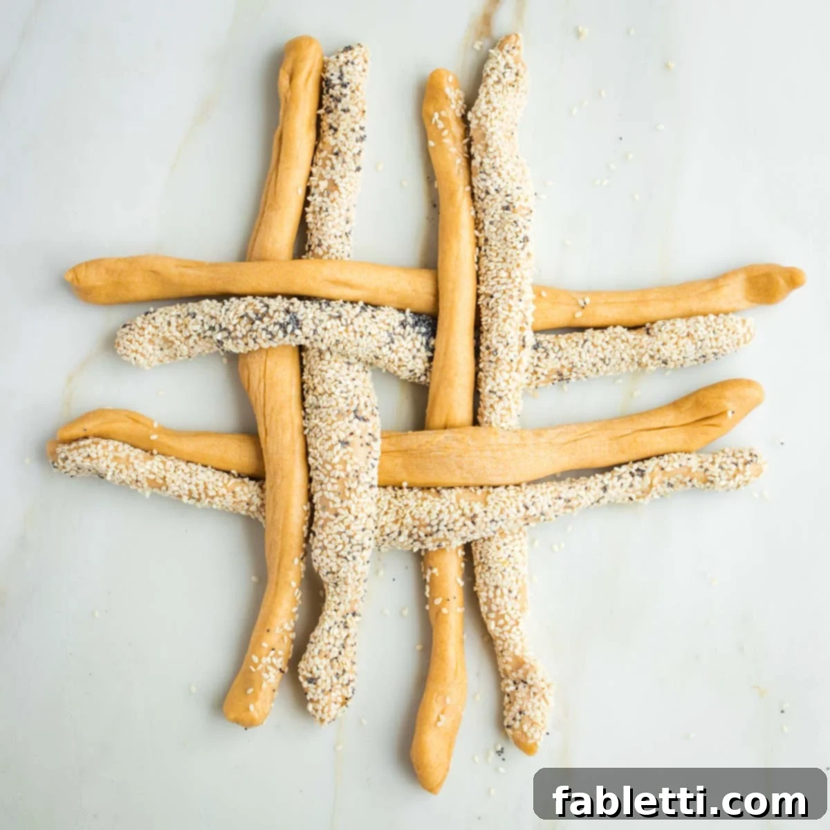 Pillowy Sweet Challah Crown 27 A grid formed by four plain challah dough ropes and four seeded ropes, arranged in an alternating over-and-under pattern, resembling a tic-tac-toe board.