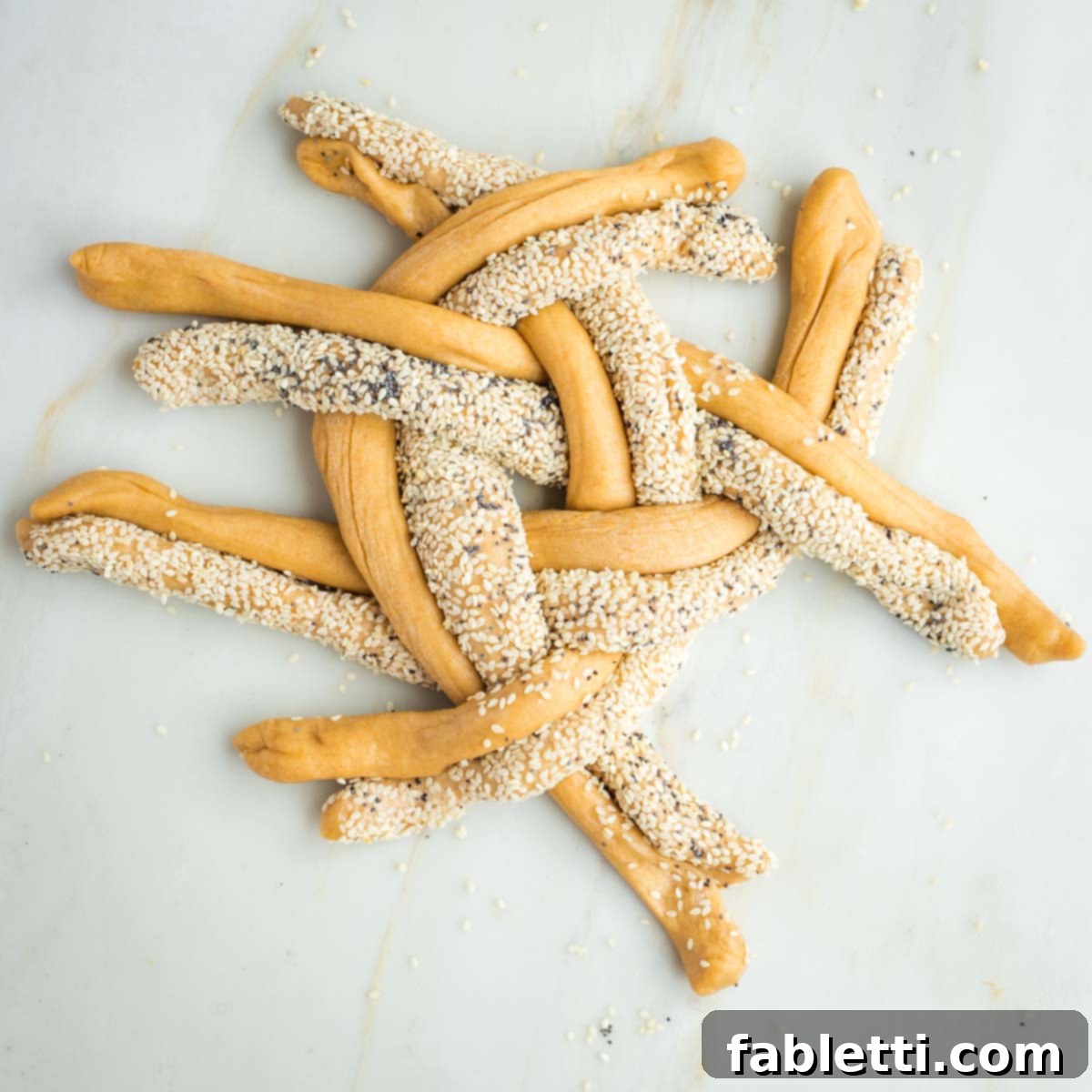 Pillowy Sweet Challah Crown 29 Pairs of seeded and plain challah dough strands are intricately crossed over and under in a continuous pattern, gradually forming a tightly braided round loaf.