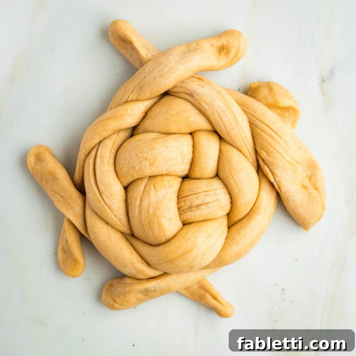Pillowy Sweet Challah Crown 37 Circular pattern of weaving over and under on ropes of dough.