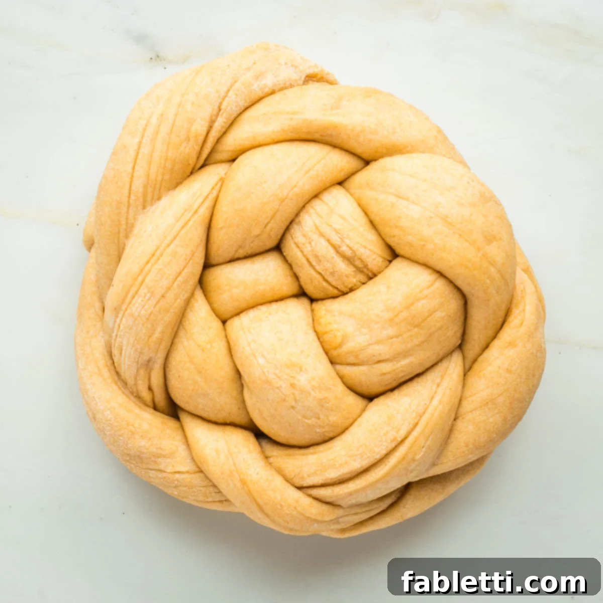 Pillowy Sweet Challah Crown 38 Round loaf of bread created with a braided pattern.