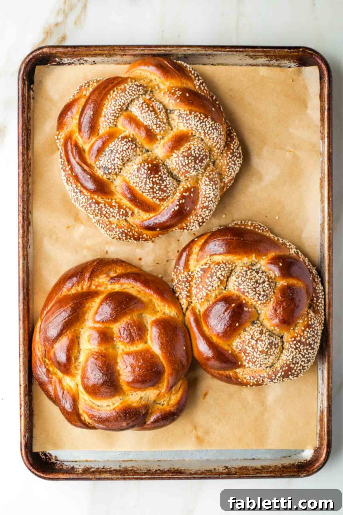 Pillowy Sweet Challah Crown 42 Golden brown, round loaves of braided challah bread.