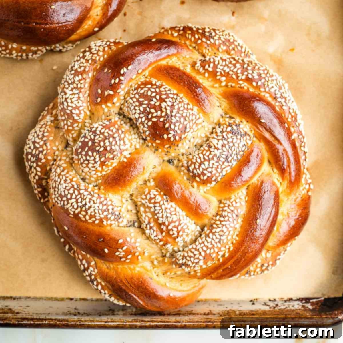 Pillowy Sweet Challah Crown 44 Golden brown, partially seeded, braided loaf of round challah.