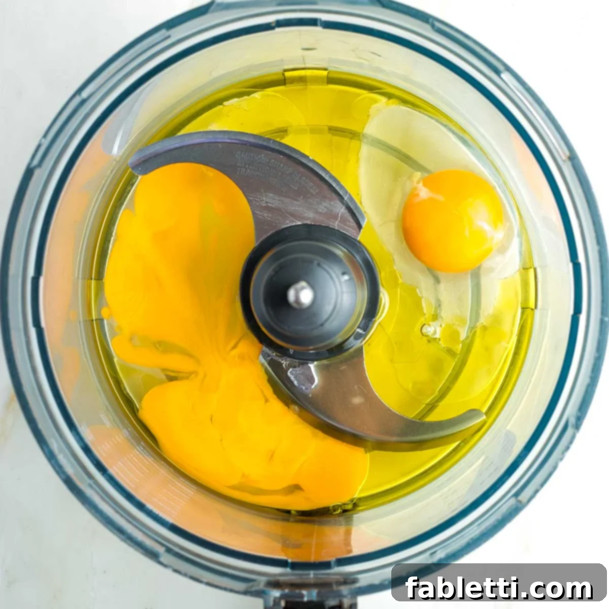 Pillowy Sweet Challah Crown 8 Eggs and olive oil measured into the bowl of a food processor, ready for mixing.