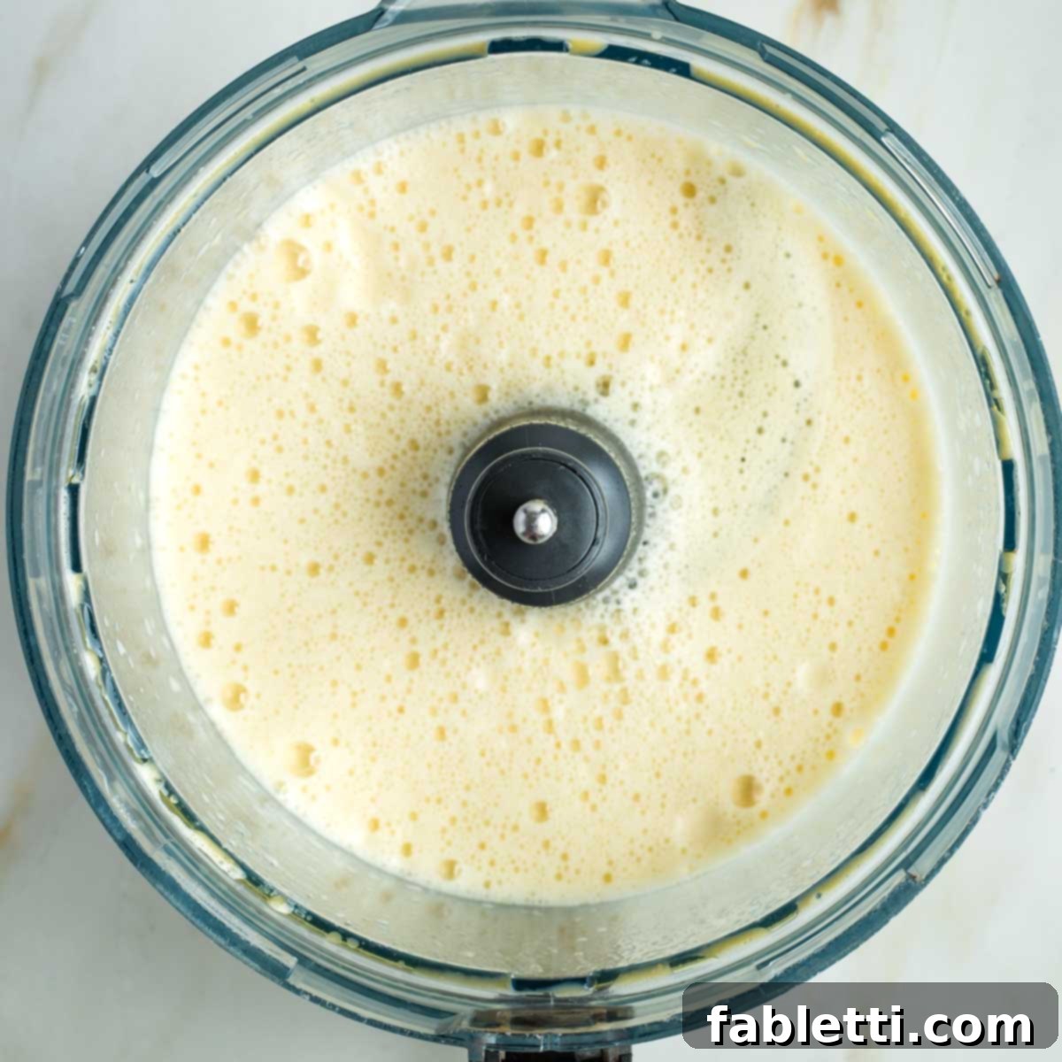 Pillowy Sweet Challah Crown 10 A frothy mixture of emulsified eggs and oil with the bubbly, proofed yeast mixture added, all swirling in the food processor bowl.