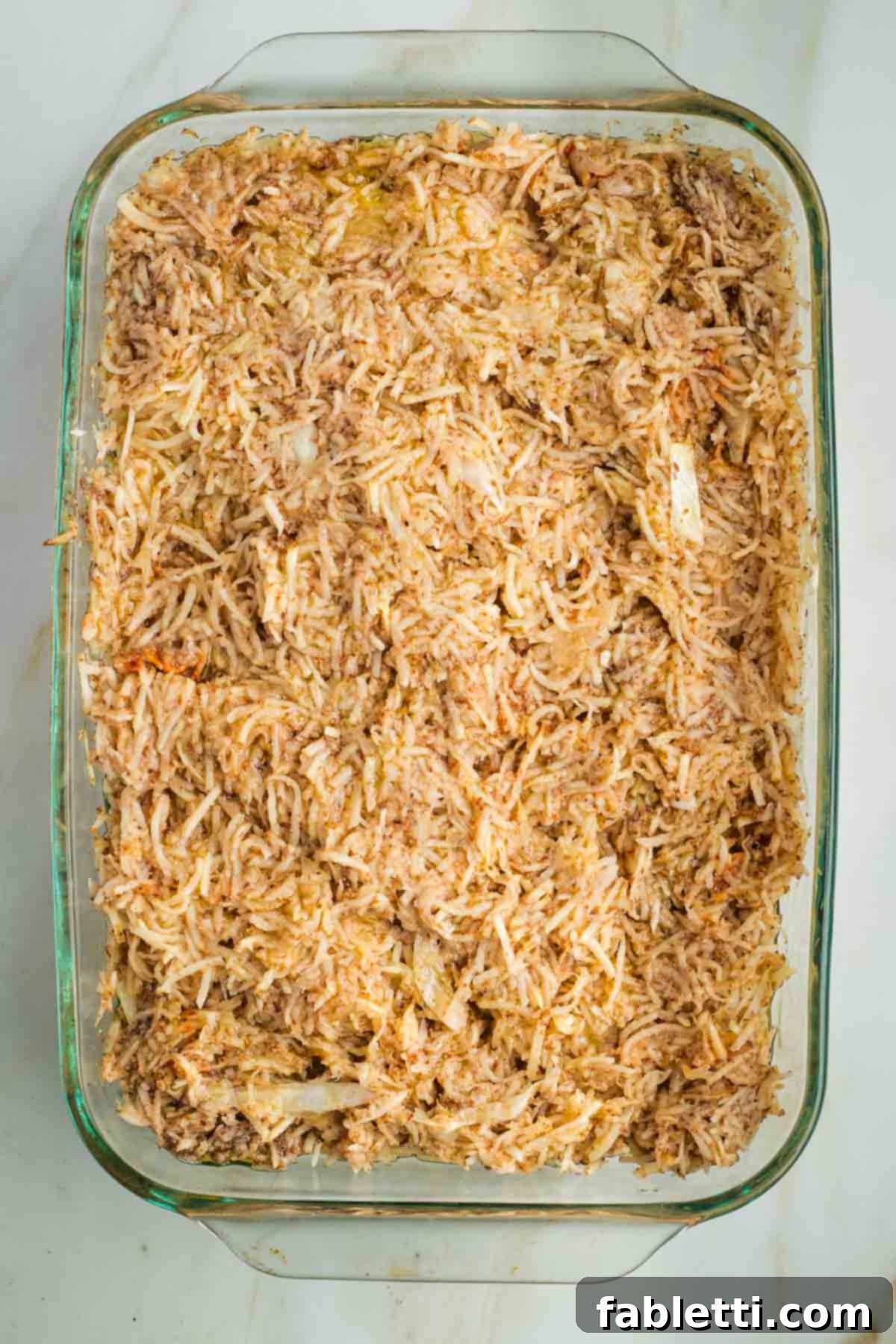 Ultimate Vegan Potato Kugel 12 Glass baking dish filled with uncooked shredded potato mixture, shimmering with oil.