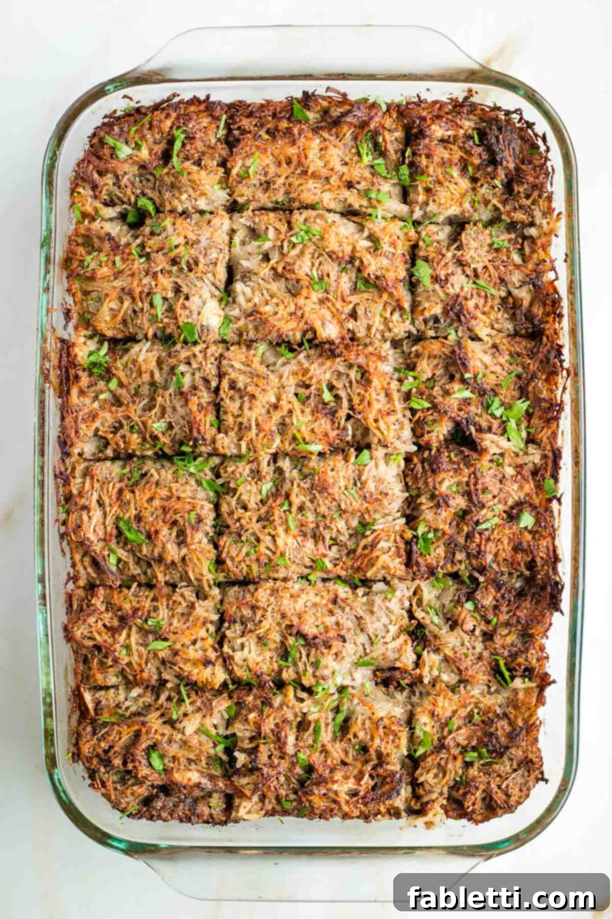 Ultimate Vegan Potato Kugel 14 Golden-brown potato kugel cut into squares and sprinkled with fresh green parsley.