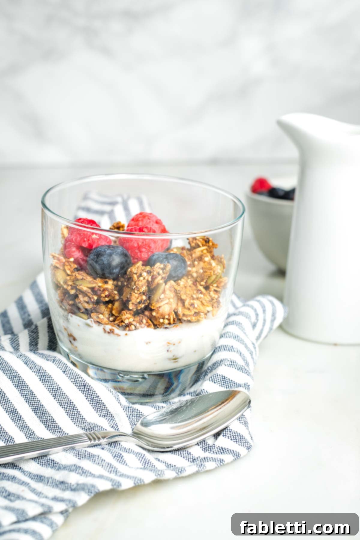 Cozy Pumpkin Spice Granola 2 Glass with granola and milk, topped with fresh raspberries and blueberries.