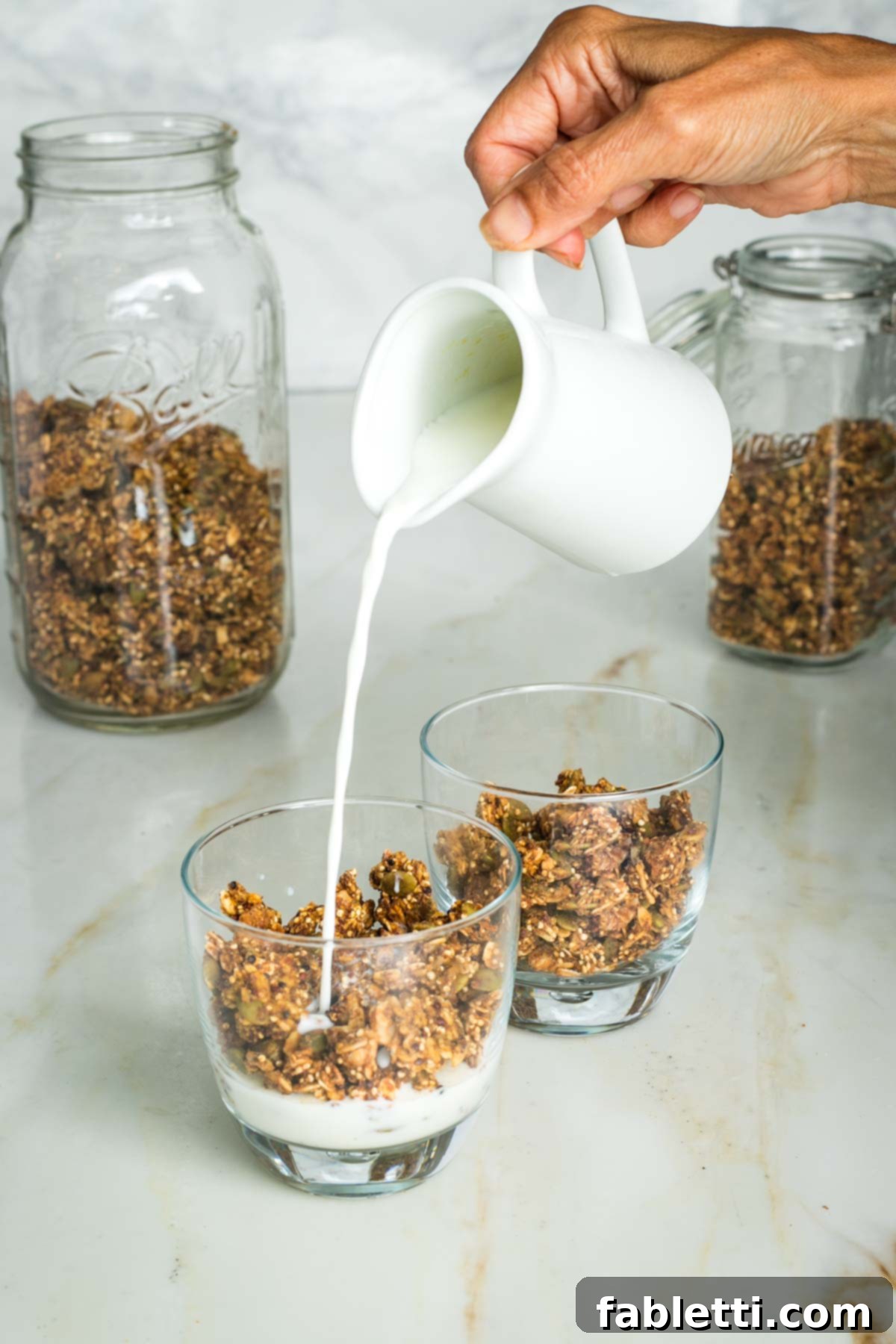 Cozy Pumpkin Spice Granola 16 Pouring milk into a glass with granola.