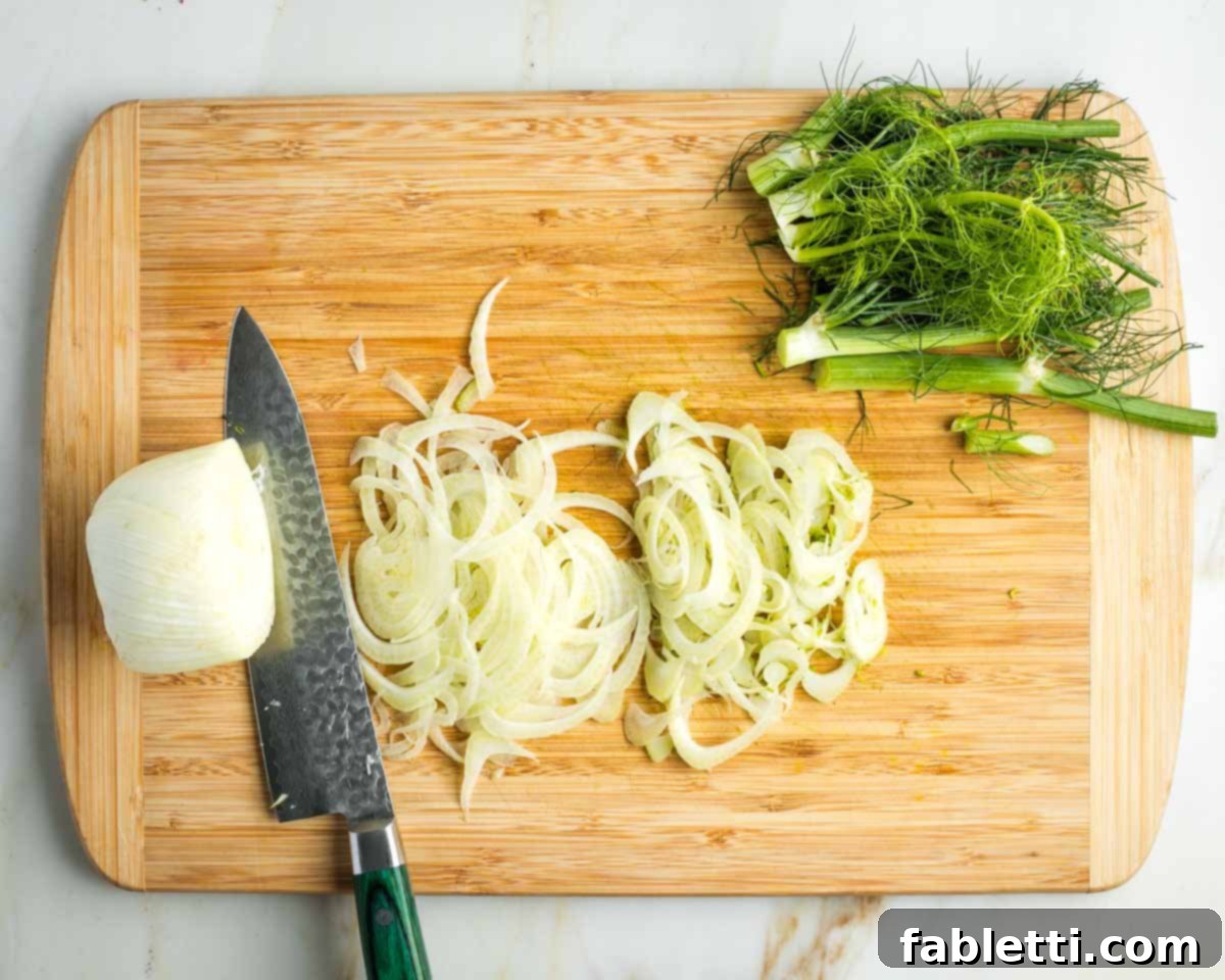 Vibrant Apple Fennel Farro Salad with Pomegranate Gems 12 The feathery fronds have been removed from the fennel bulb, which is now being cut incredibly thinly across its middle using a sharp knife, revealing its delicate layers.