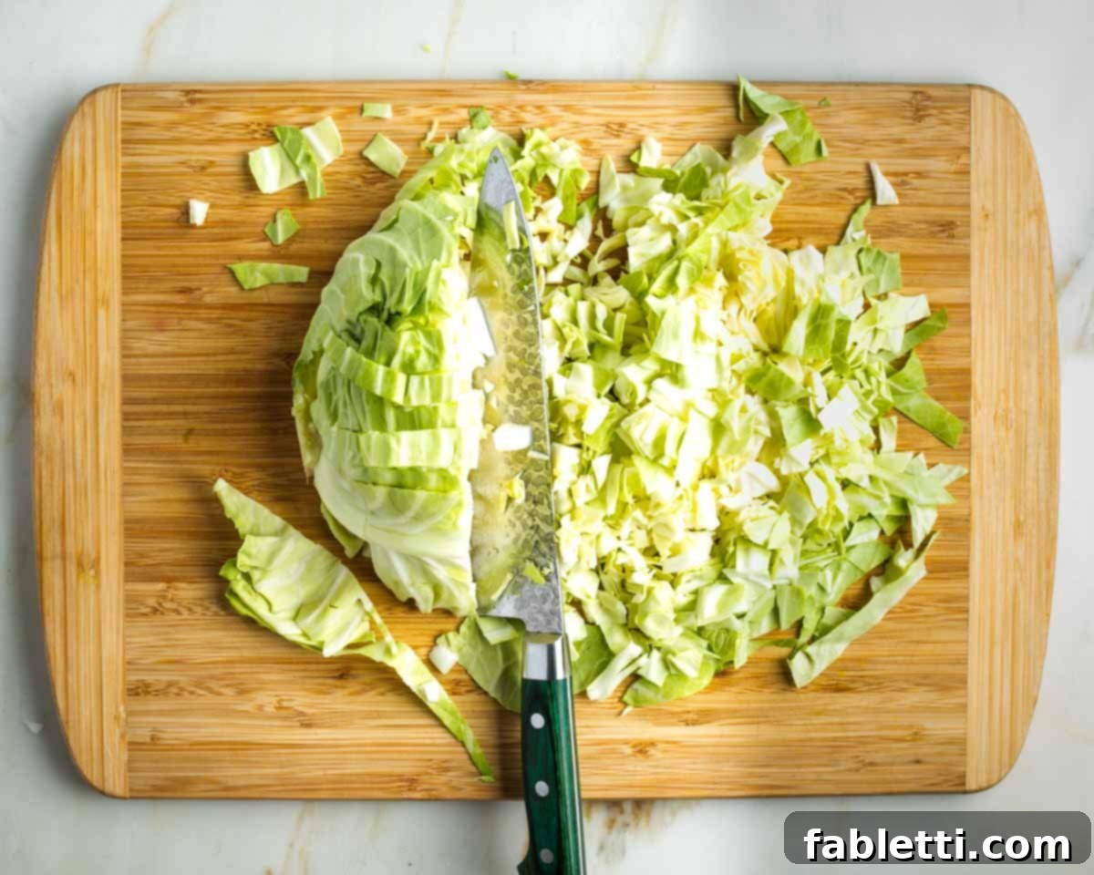 Vibrant Apple Fennel Farro Salad with Pomegranate Gems 7 Demonstration of how to roughly chop green cabbage into small, manageable cubes for a salad, illustrating a systematic cutting method.