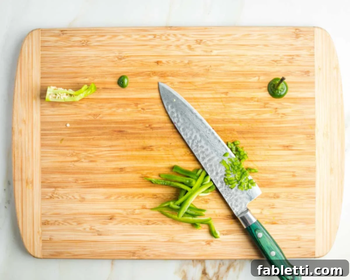 Vibrant Apple Fennel Farro Salad with Pomegranate Gems 9 Close-up showing the process of seeding and finely dicing a jalapeno pepper into small, uniform pieces, ready for inclusion in the salad.