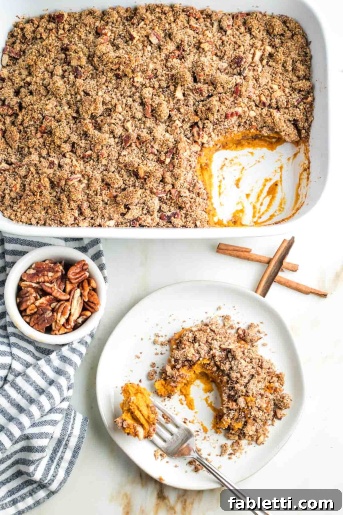 Golden Maple Pecan Sweet Potato Casserole 2 A perfectly scooped serving of Maple Pecan Sweet Potato Casserole on a white plate, showcasing the creamy orange filling and golden, crunchy pecan topping.