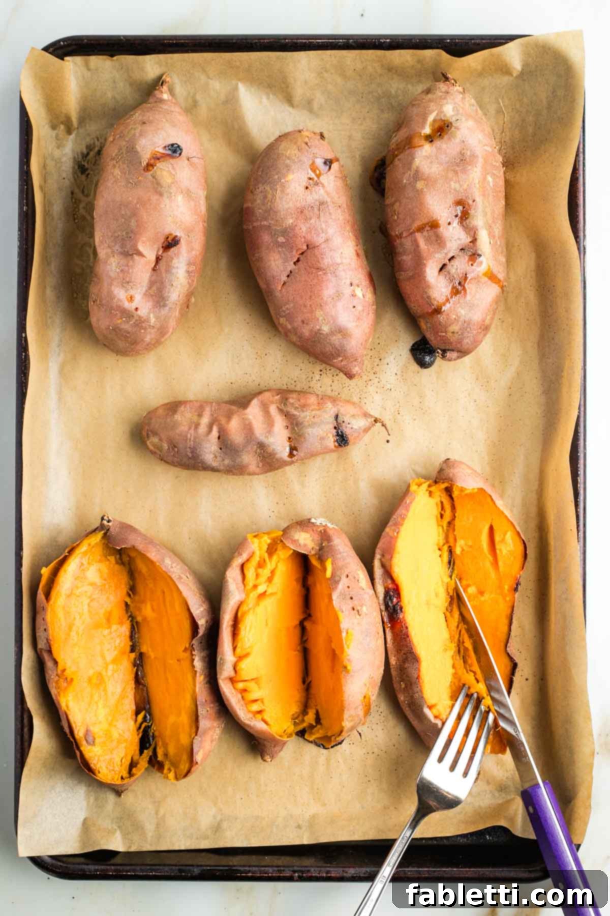 Golden Maple Pecan Sweet Potato Casserole 11 Cutting baked sweet potatoes in half lengthwise on a tray, revealing their soft, vibrant orange flesh.