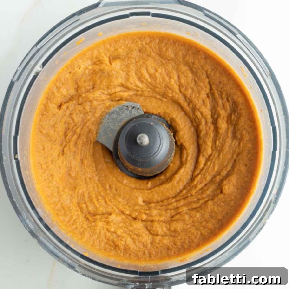 Golden Maple Pecan Sweet Potato Casserole 14 Smooth, vibrant orange sweet potato mixture in the bowl of a food processor after blending, showing its creamy texture.