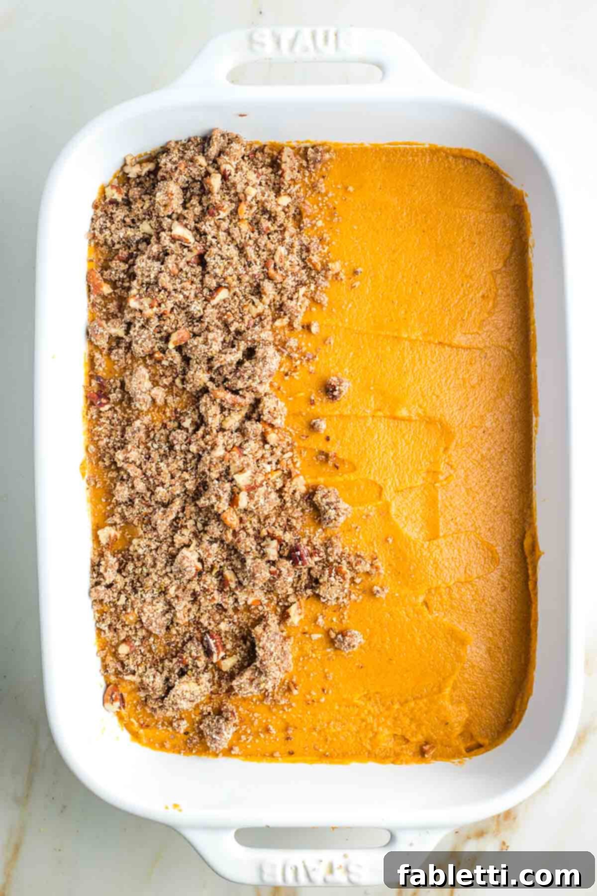 Golden Maple Pecan Sweet Potato Casserole 16 White baking dish, filled with pureed sweet potatoes, with half of the surface generously topped with the maple pecan crumble mixture.