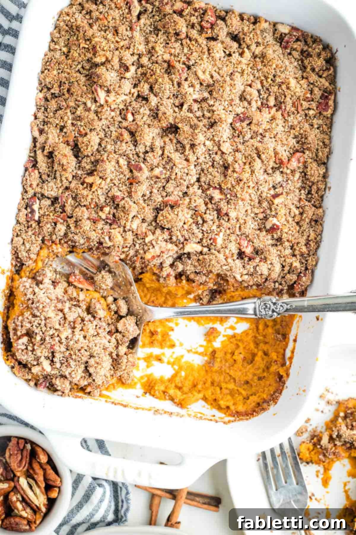 Golden Maple Pecan Sweet Potato Casserole 18 A large serving spoon scooping out a portion of the sweet potato casserole, revealing the creamy orange filling beneath the crunchy maple pecan topping.
