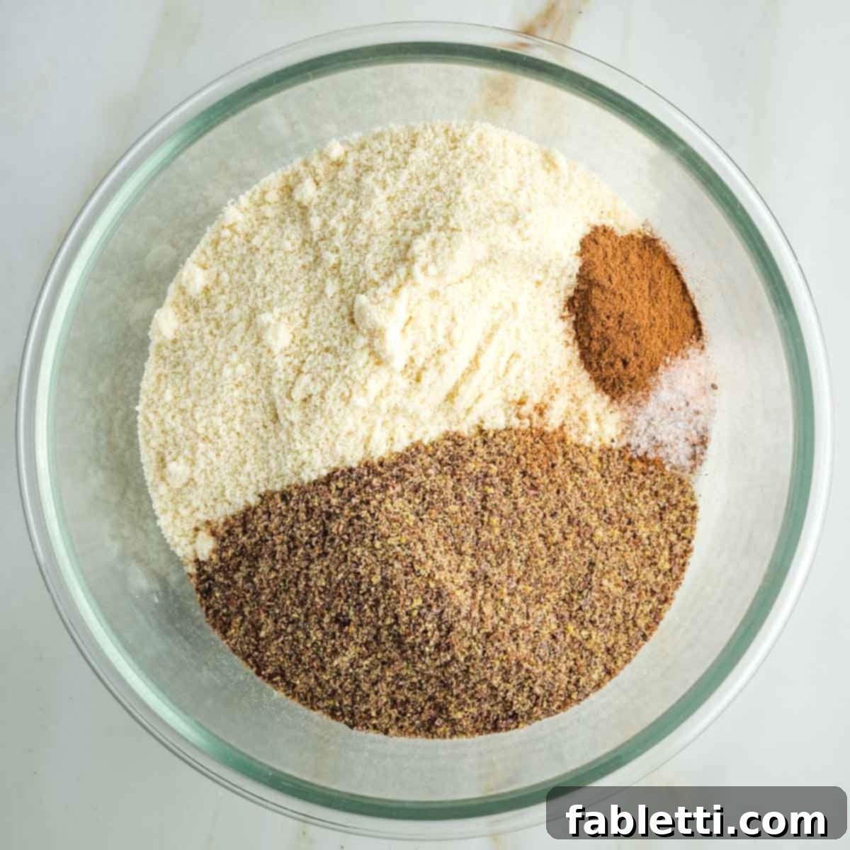 Golden Maple Pecan Sweet Potato Casserole 7 Glass bowl containing almond flour, ground flax, cinnamon, allspice, and salt, ready to be mixed for the crumble topping.
