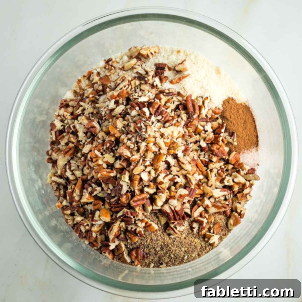 Golden Maple Pecan Sweet Potato Casserole 8 Almond flour, ground flax, chopped pecans, and spices in a glass mixing bowl, forming the base of the crumble topping.
