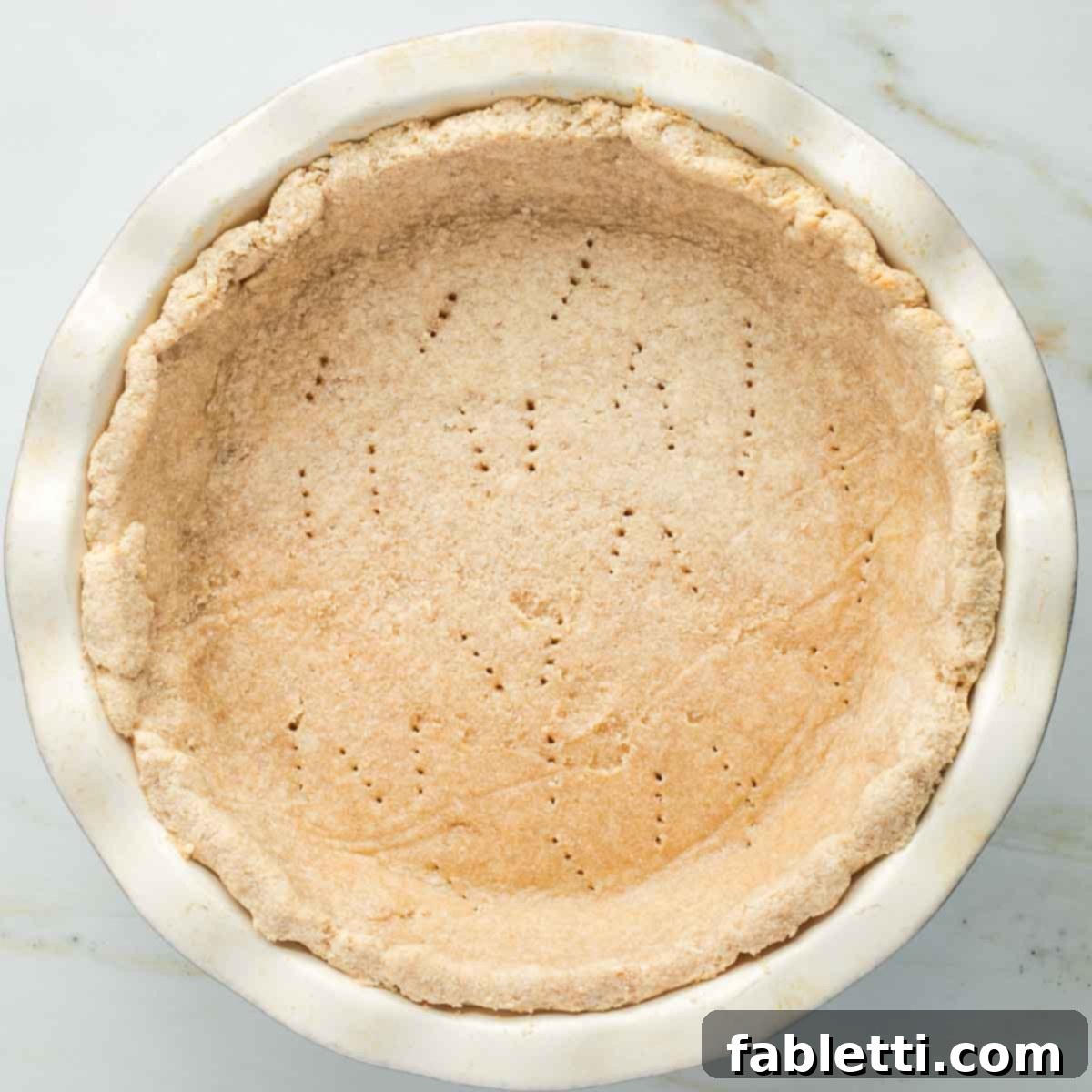 Effortless Vegan Pumpkin Pie with a Homemade Dairy-Free Crust 12 A perfectly blind-baked vegan pie crust, golden brown and firm, sitting in its pie plate, showcasing the fork tine marks.