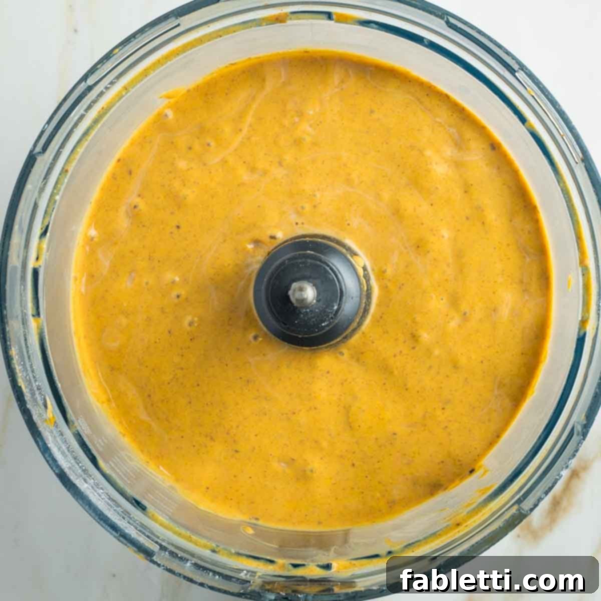 Effortless Vegan Pumpkin Pie with a Homemade Dairy-Free Crust 14 The vegan pumpkin pie filling being blended in a food processor, demonstrating its transformation into a smooth and creamy consistency.