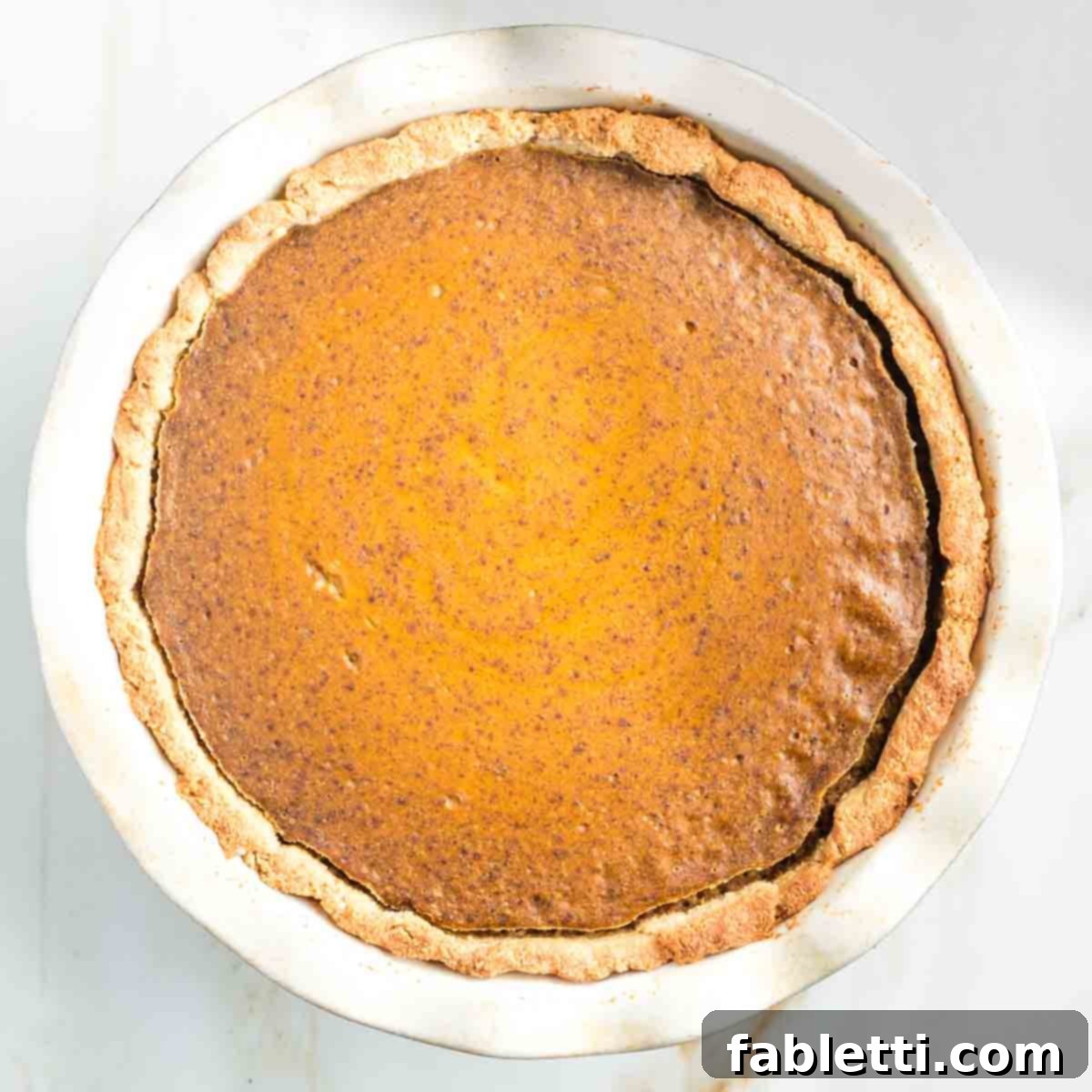 Effortless Vegan Pumpkin Pie with a Homemade Dairy-Free Crust 16 A freshly baked vegan pumpkin pie cooling on a wire rack or stove grates, allowing air to circulate for proper setting.
