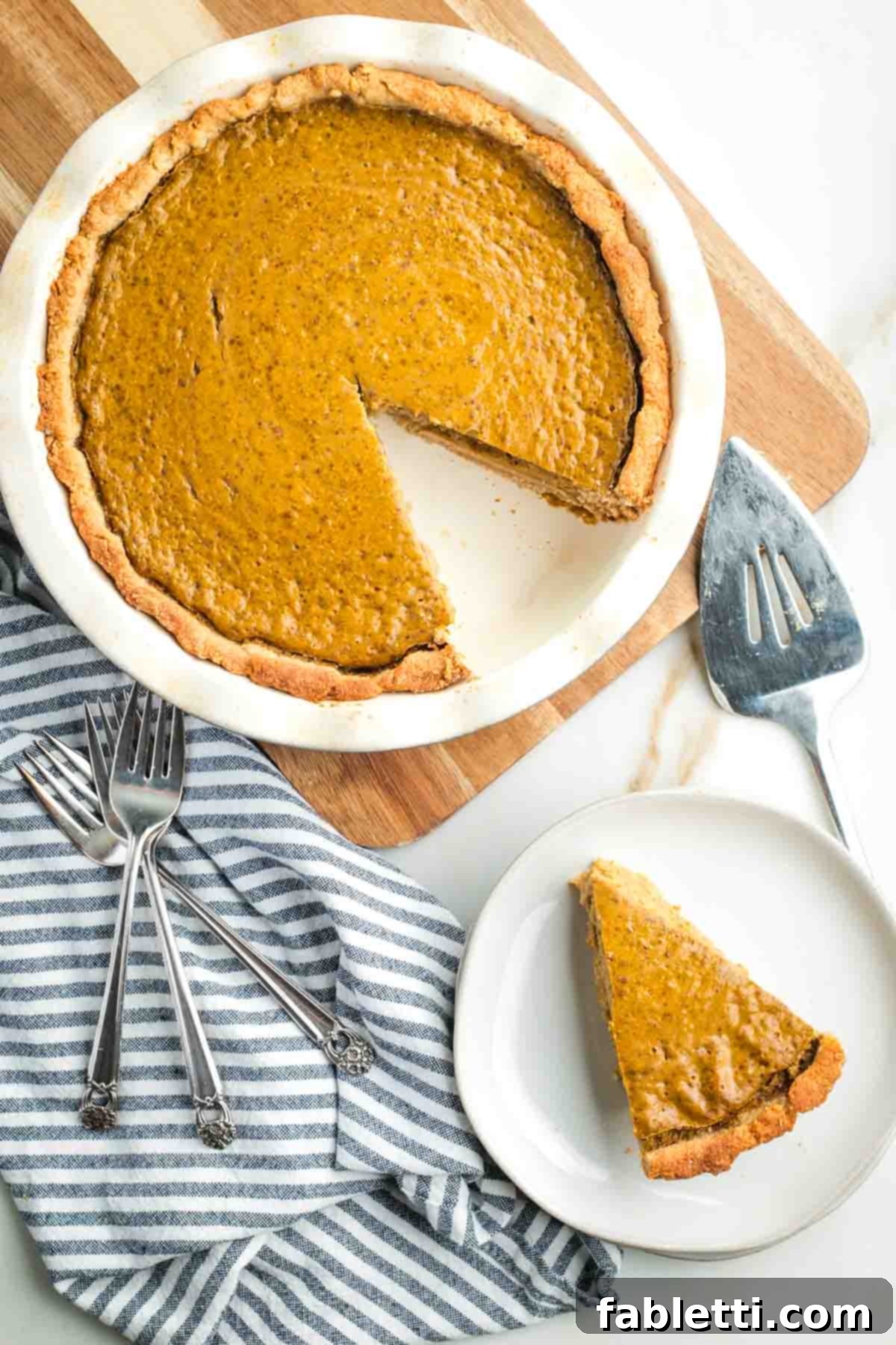 Effortless Vegan Pumpkin Pie with a Homemade Dairy-Free Crust 17 A delicious vegan pumpkin pie with one slice removed and placed onto a white plate, ready to be served.