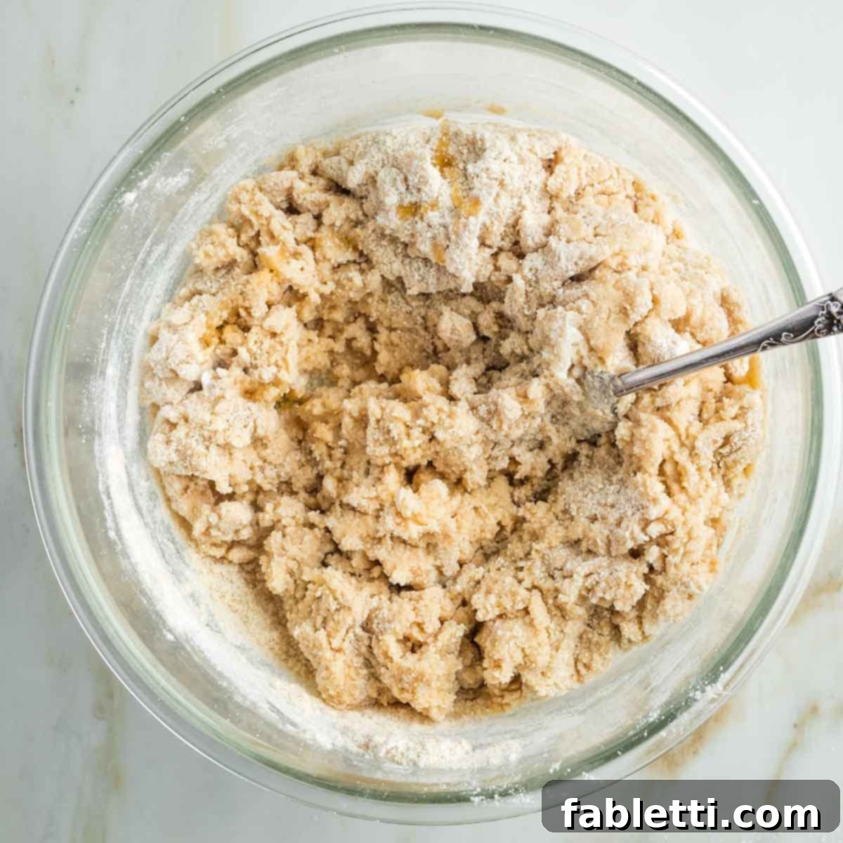 Effortless Vegan Pumpkin Pie with a Homemade Dairy-Free Crust 7 A fork is used to mix the vegan pie dough together in a glass bowl, showing the crumbly yet cohesive texture.