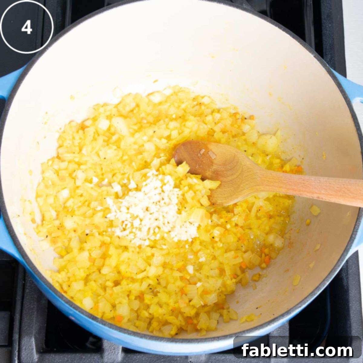 Golden Vegan Carrot Ginger Soup 11 The fragrant mixture of sautéed vegetables, ginger, and turmeric now includes minced garlic in the Dutch oven.