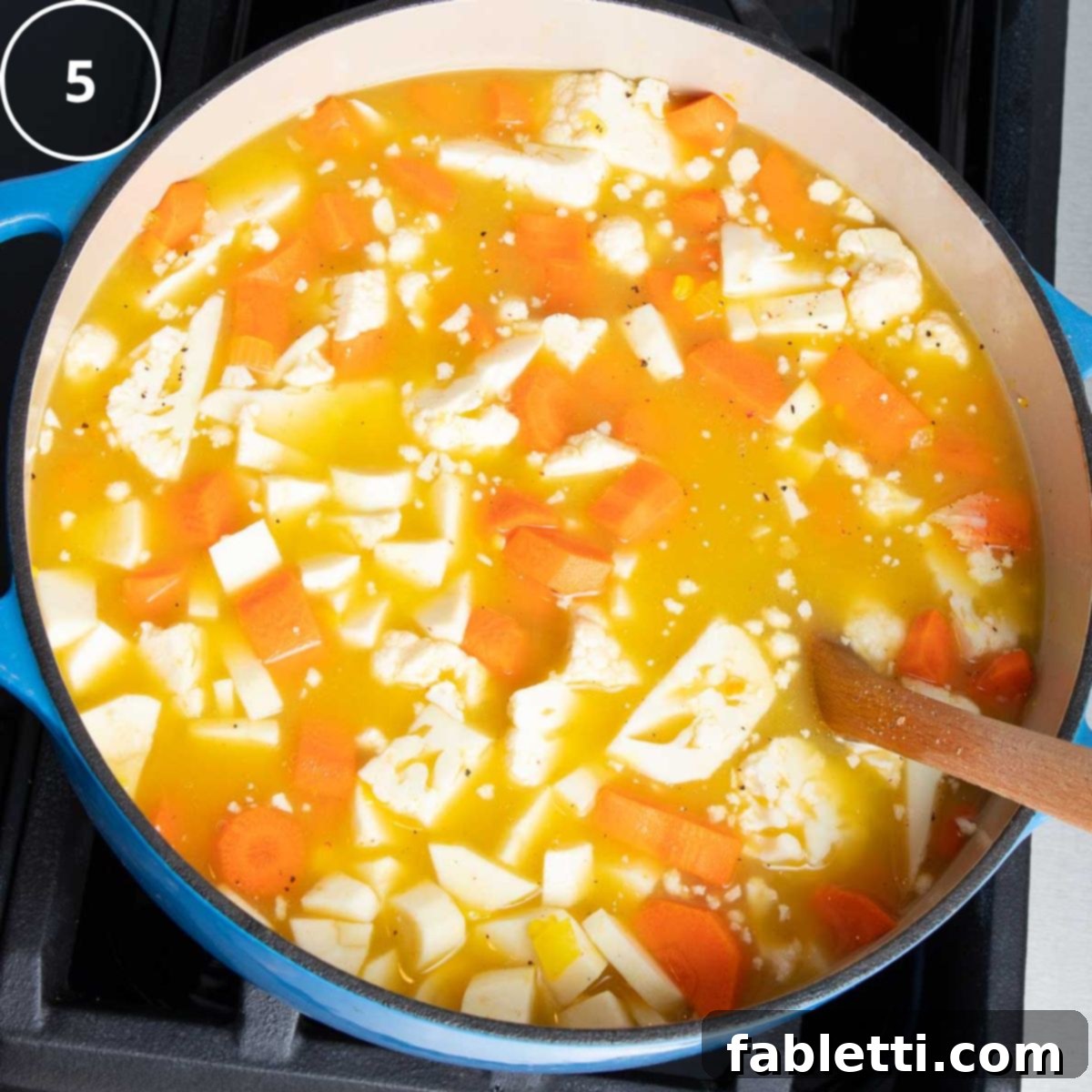 Golden Vegan Carrot Ginger Soup 12 Freshly diced carrots, parsnips, and cauliflower are added to a Dutch oven filled with simmering vegetable broth.