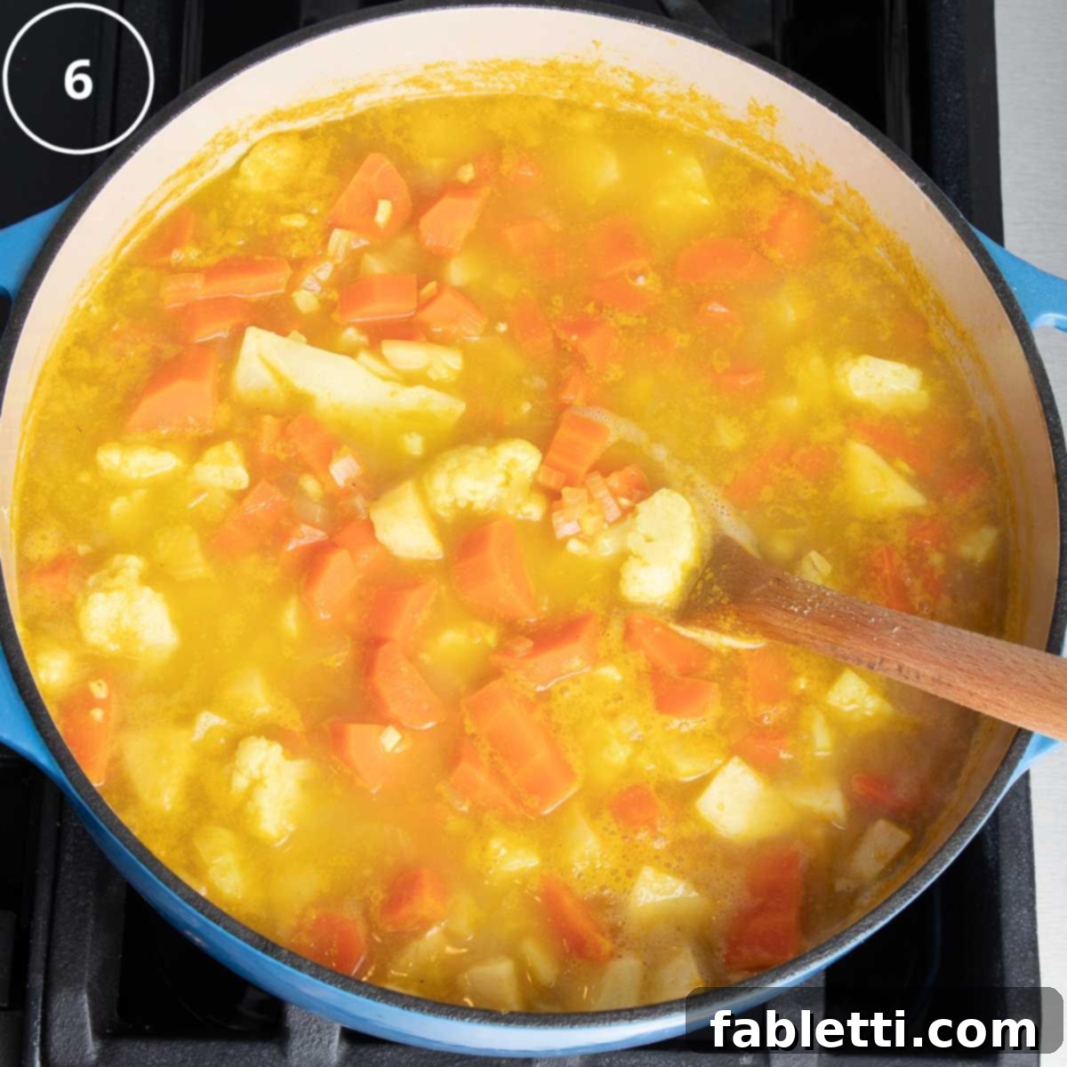 Golden Vegan Carrot Ginger Soup 13 A close-up view of tender, cooked vegetables simmering in a flavorful broth within a Dutch oven, indicating they are ready for pureeing.