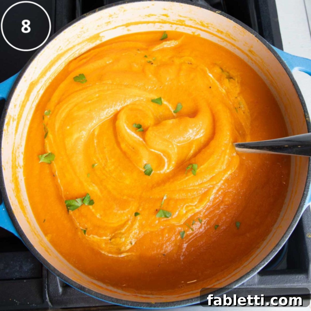 Golden Vegan Carrot Ginger Soup 15 Bright orange carrot soup, artfully swirled with vegan sour cream and garnished with fresh green herbs, is ready to be served from a Dutch oven.