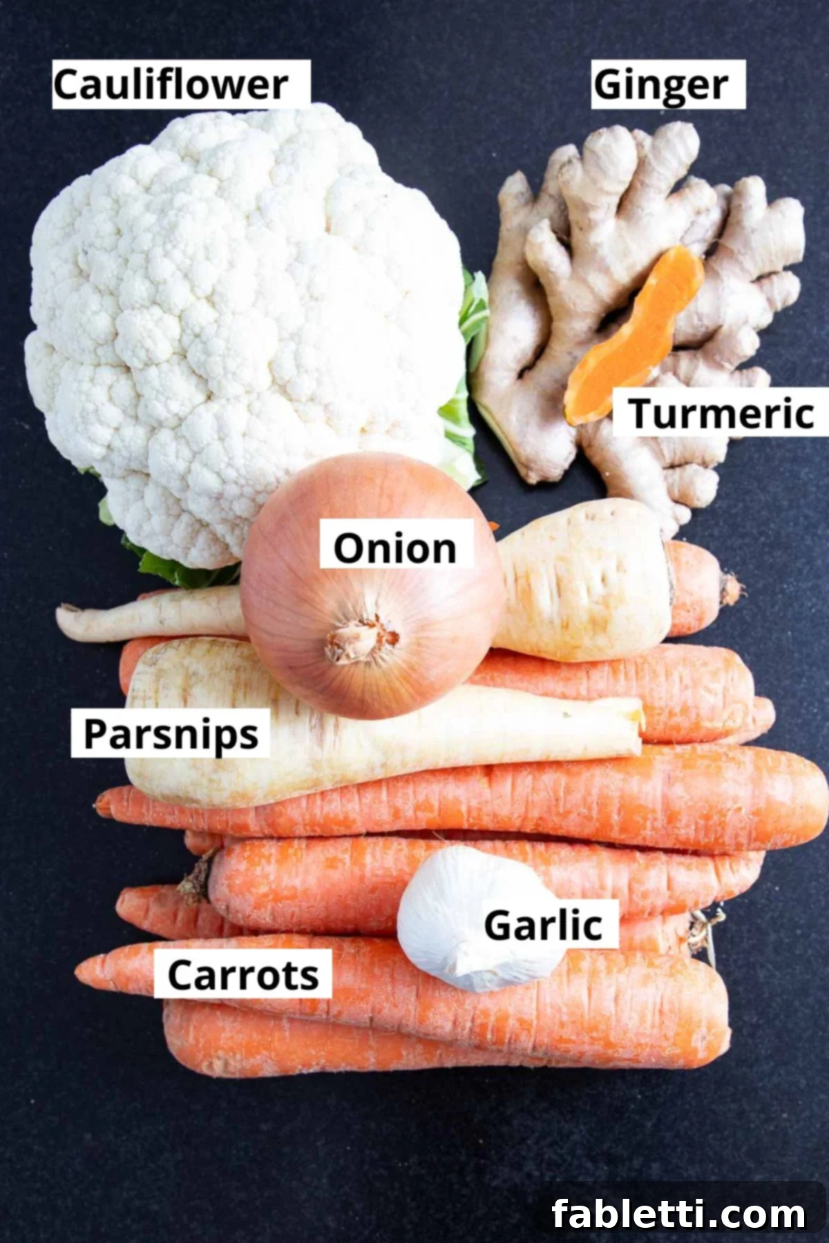 Golden Vegan Carrot Ginger Soup 4 A vibrant flat lay showcasing all the fresh, prepped ingredients for the carrot ginger soup, including diced carrots, parsnips, cauliflower, onions, minced ginger, turmeric, and garlic.