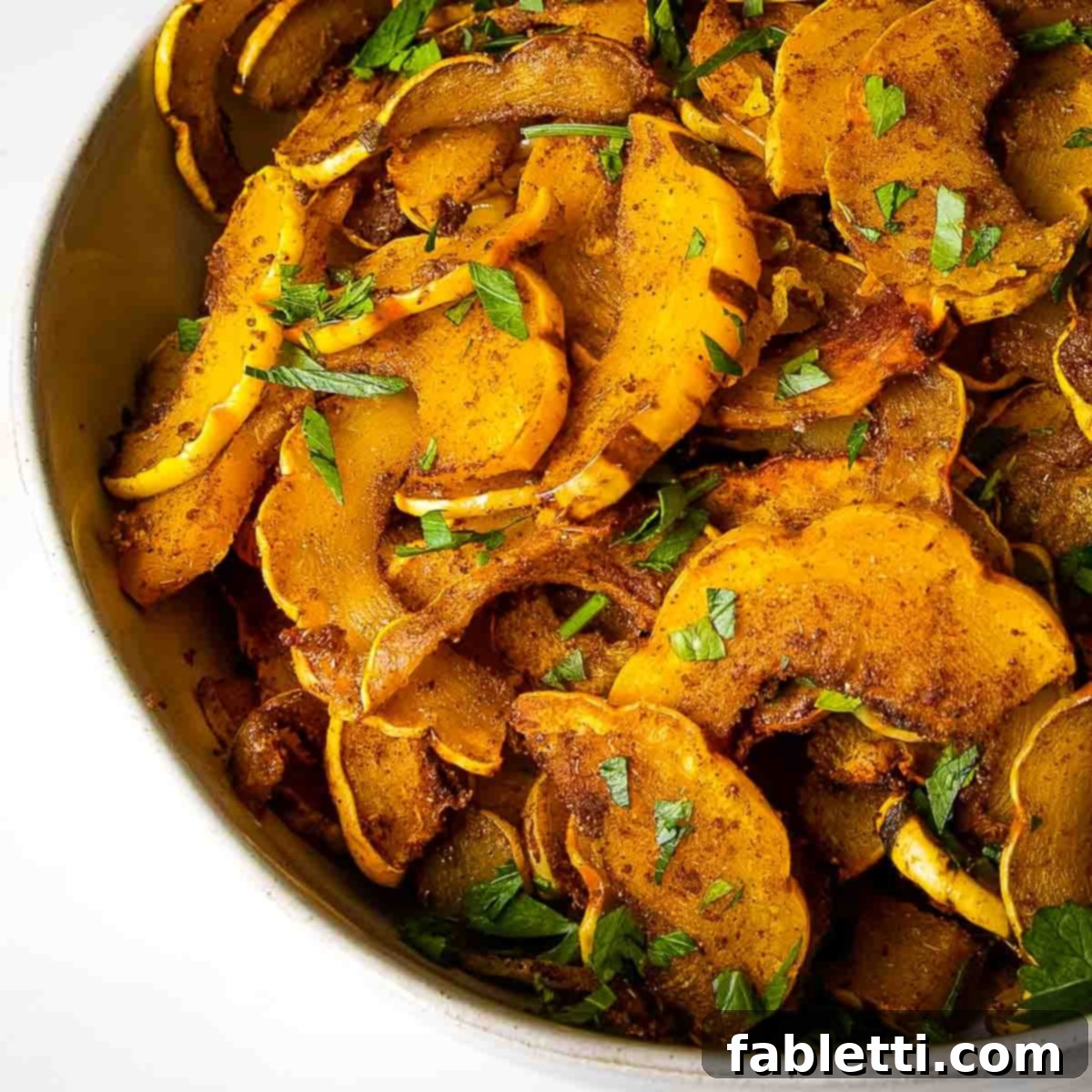 Golden Roasted Delicata Squash 12 Bowl of half moon slices of roasted and spiced delicata squash sprinkled with fresh herbs.