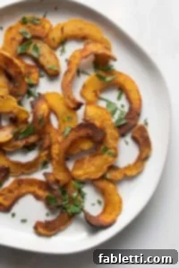 Golden Roasted Delicata Squash 13 Round plate with half moon shaped roasted delicata squash sprinkled with parsley.