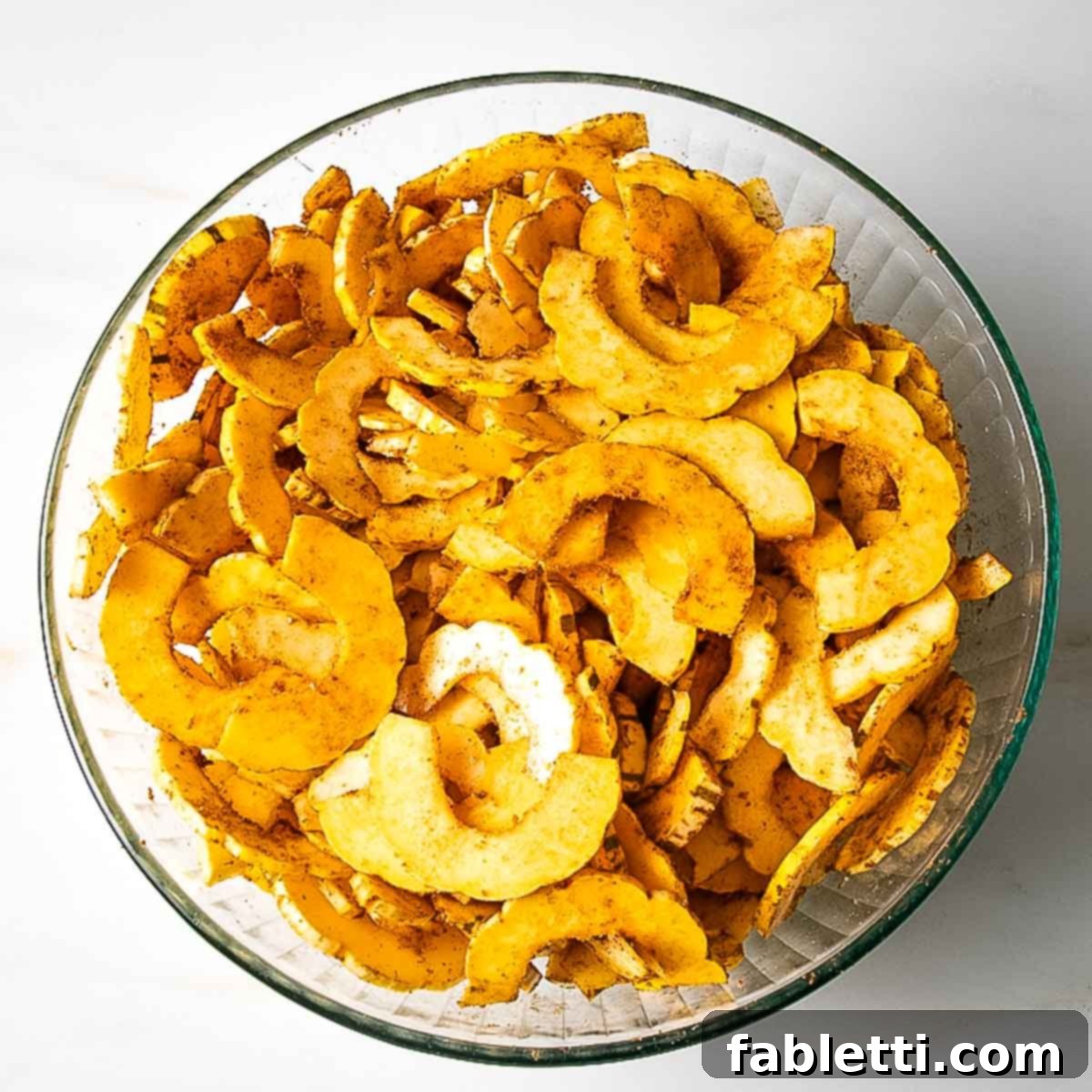 Golden Roasted Delicata Squash 8 Glass bowl filled with spiced delicata half moon thin slices.