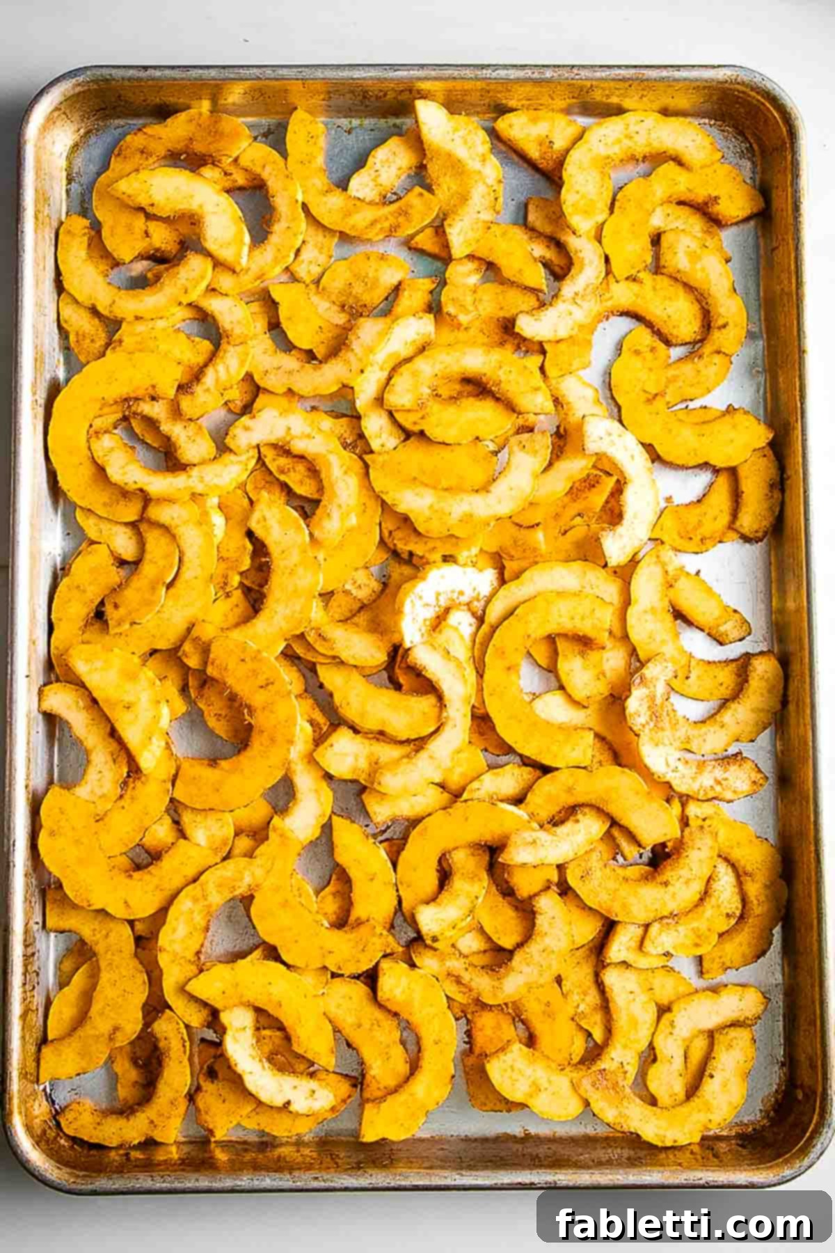Golden Roasted Delicata Squash 9 Single layer of half moon shaped winter squash on a baking tray.