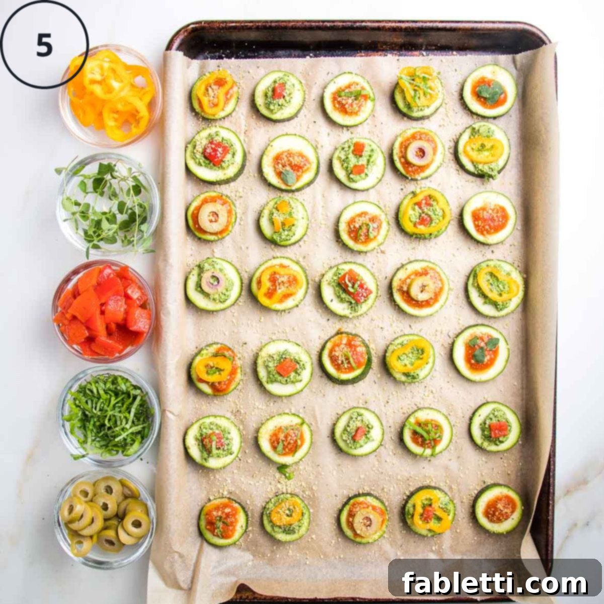 Mini Zucchini Pizzas 9 Baking tray of zucchini pizza bites with small dishes on the side with toppings.