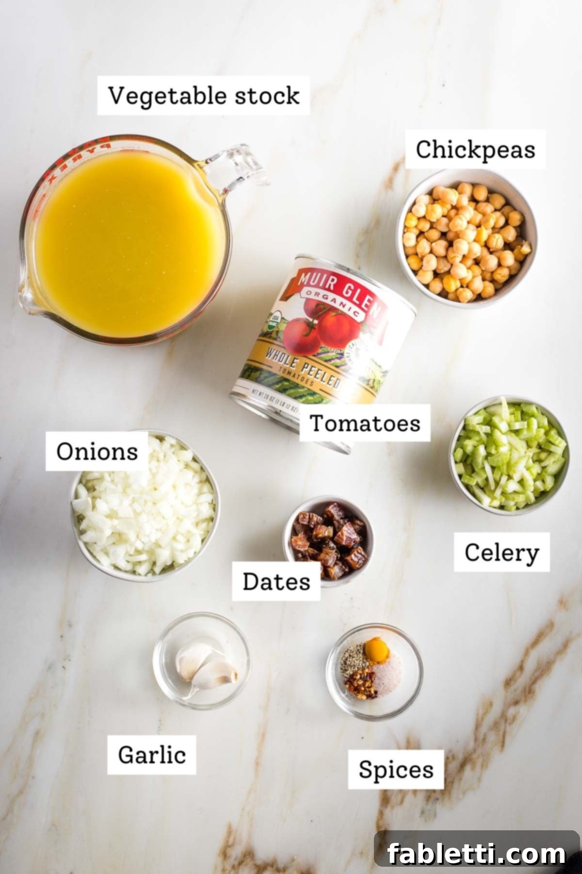 Creamy Vegan Tomato Soup 4 Labled ingredients for dairy-free tomato soup: vegetable stock, canned tomatoes, chickpeas, onions, dates, celery, garlic, and spices.