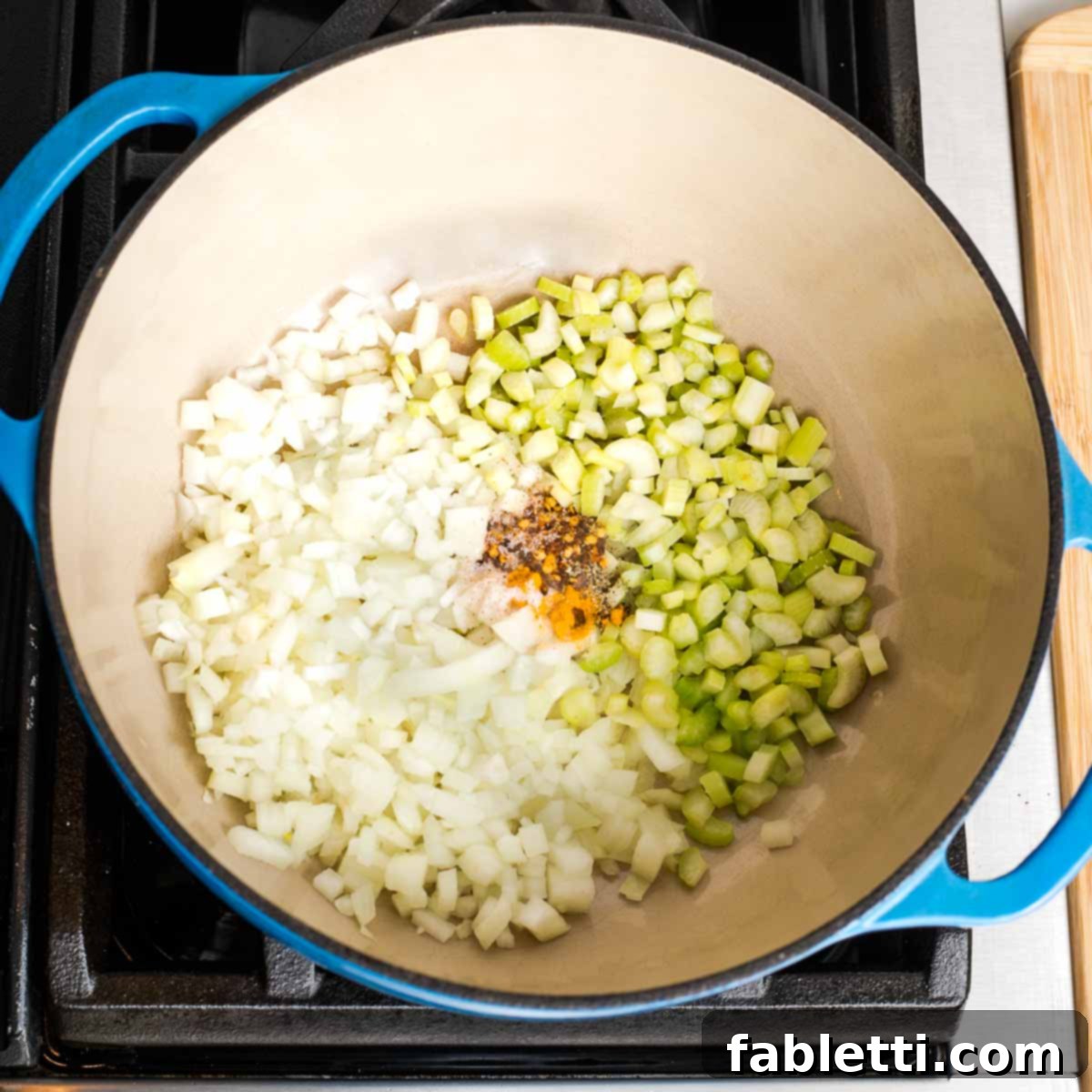 Creamy Vegan Tomato Soup 5 Dutch oven with chopped onions, celery, and spices simmering.