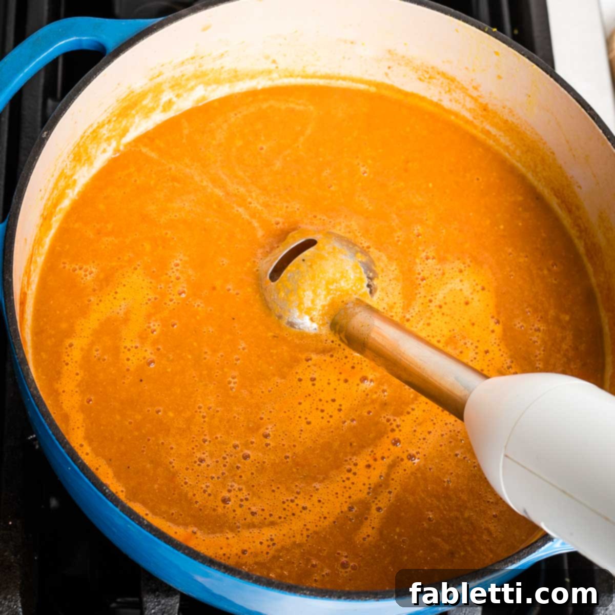 Creamy Vegan Tomato Soup 10 An immersion blender pureeing tomato soup directly in a dutch oven.