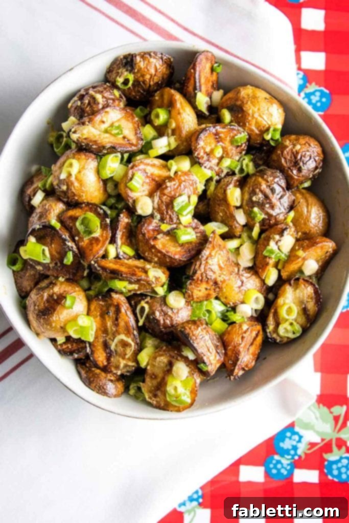Smoky Grilled Potato Salad 11 Grilled potato salad, sprinkled with scallions in a white bowl.