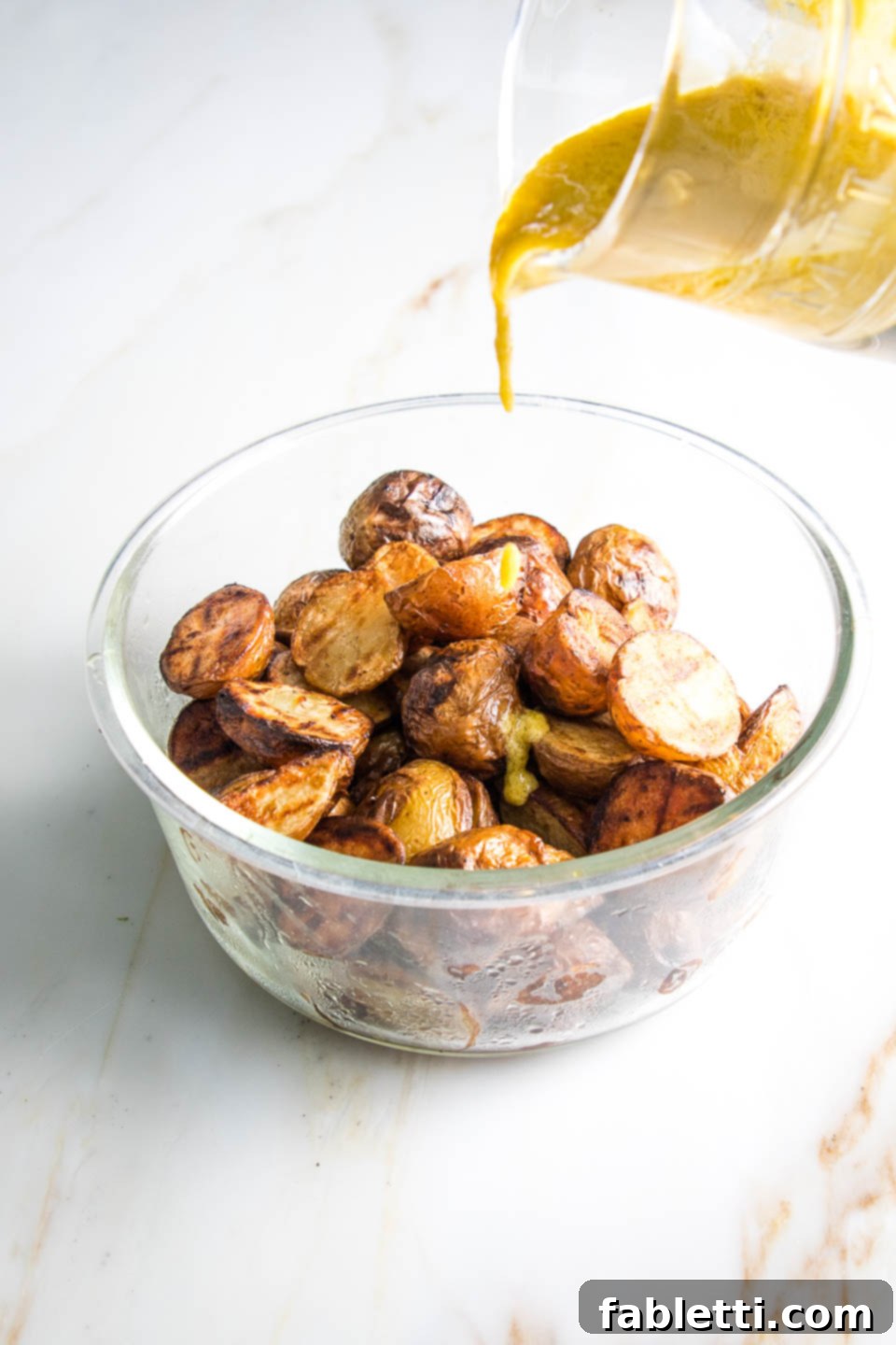 Smoky Grilled Potato Salad 7 Pouring mustard aioli over a bowl of grilled potatoes
