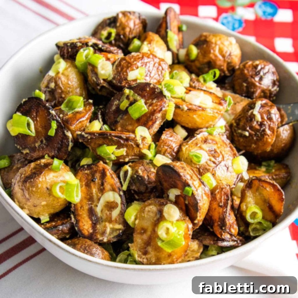 Smoky Grilled Potato Salad 9 Red and White checkered background with a white bowl filled with potato salad sprinkled with scallions.